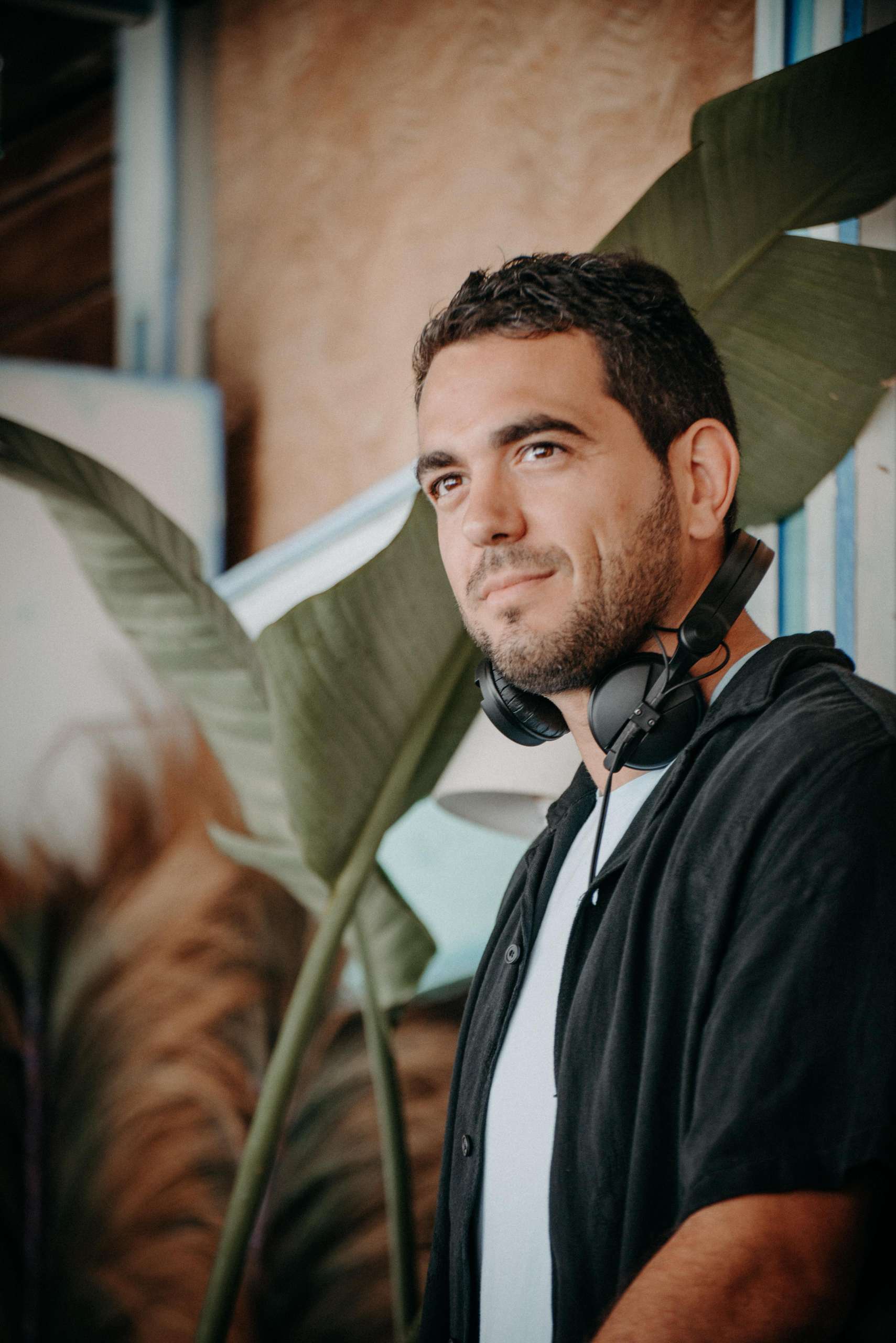 Portrait élégant de Flanker DJ à Anjuna Èze, avec casque autour du cou, symbole de son univers musical premium sur la Côte d’Azur.