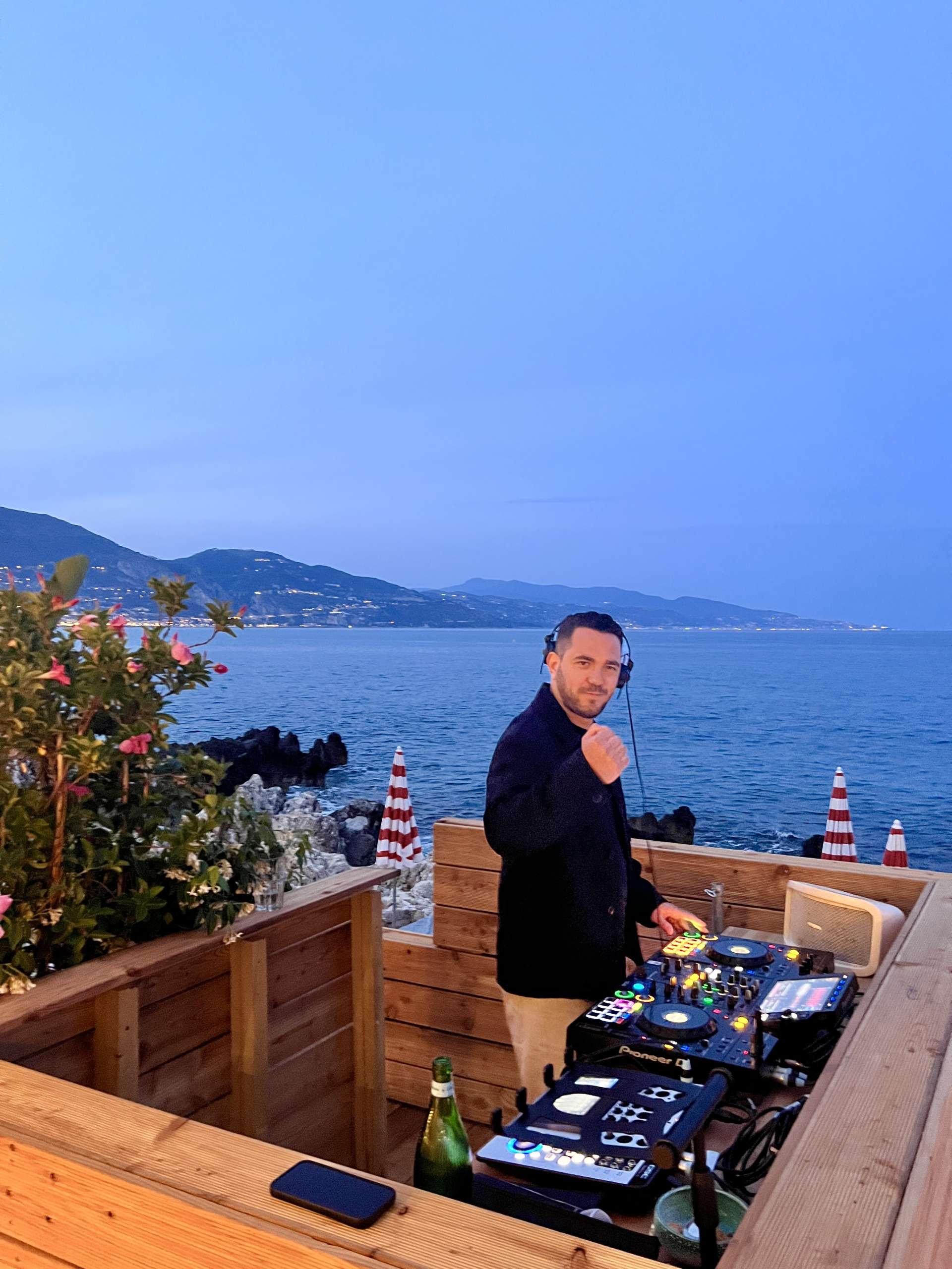 Flanker DJ en pleine performance sur la terrasse bois de La Môme Riviera à Roquebrune, face à la Méditerranée, dans une ambiance élégante et chic.
